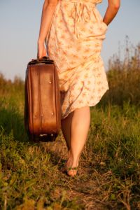 Woman with a suitcase takes on a rural road